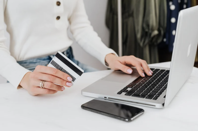 Mains tenant une carte bancaire et des pièces de monnaie.